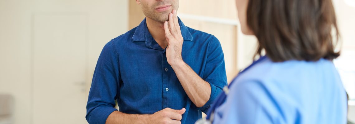 Waist up portrait of mature man explaining symptoms to nurse standing in hall of modern dental clinic, copy space